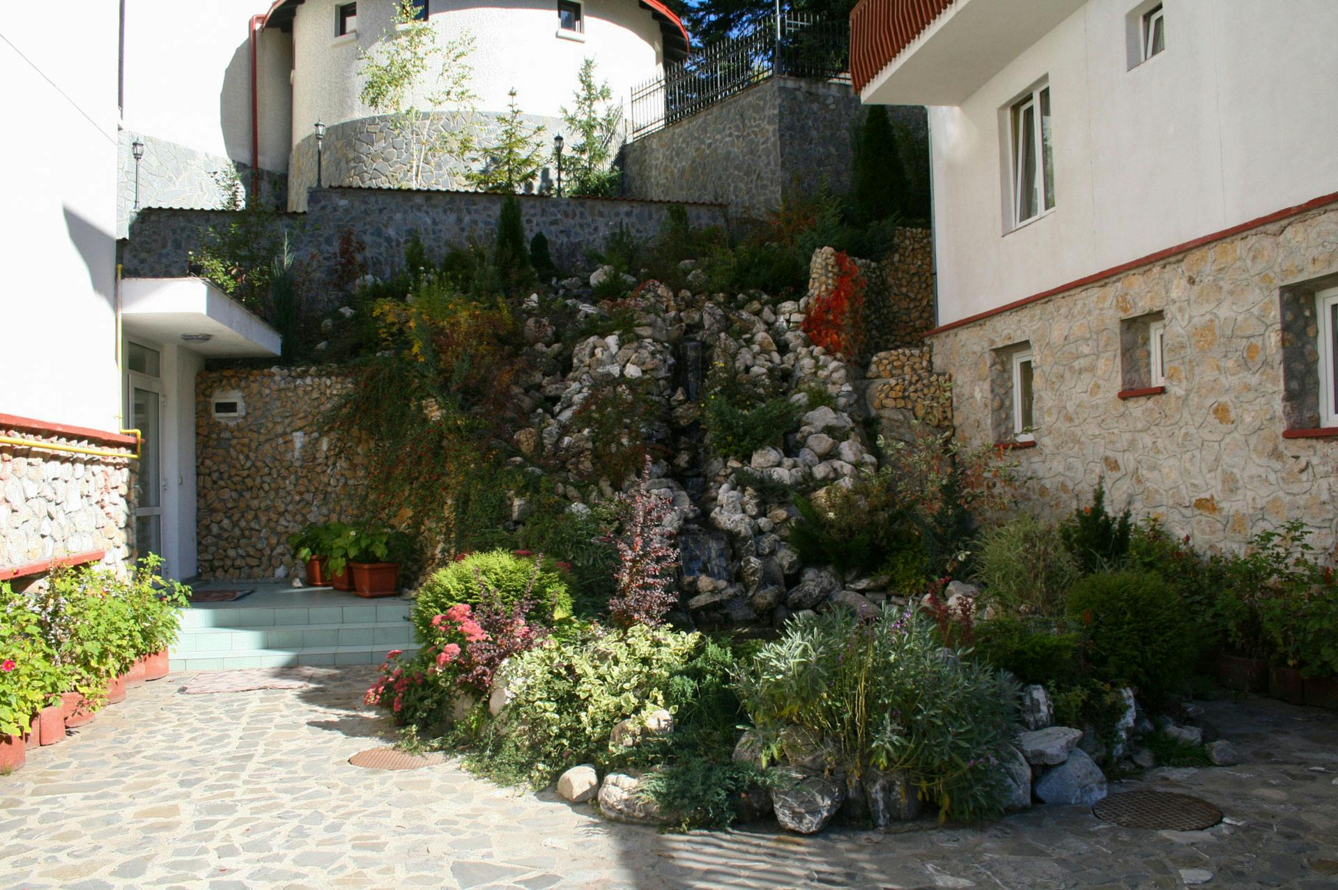 hotel cu cascada ornamentala cu flori plante si rocarie