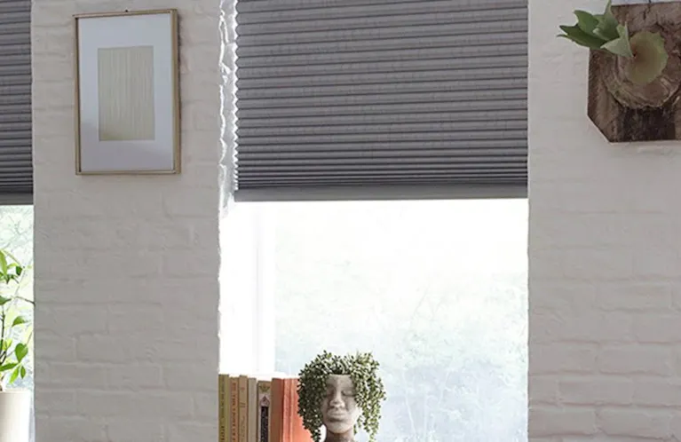 grey cellular shades among white walls in a bright sitting room
