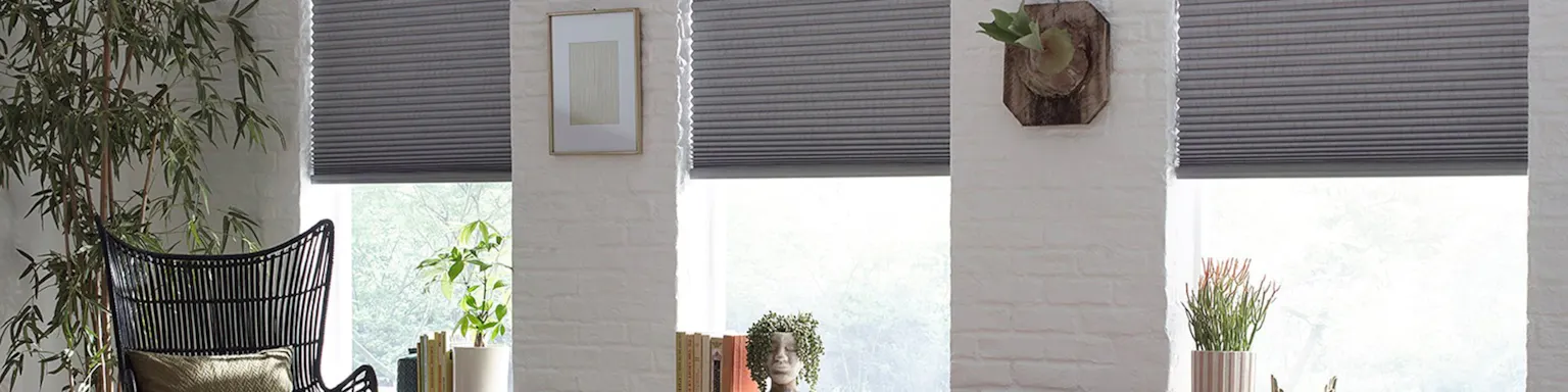 grey cellular shades among white walls in a bright sitting room