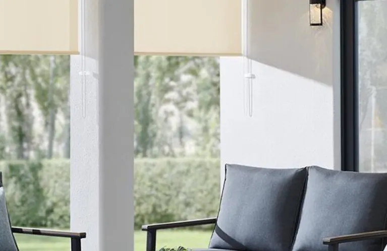 Off-white outdoor shades half lowered to block sun in an outdoor patio