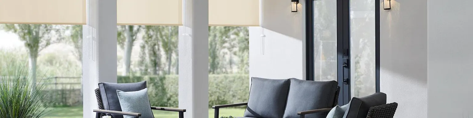 Off-white outdoor shades half lowered to block sun in an outdoor patio