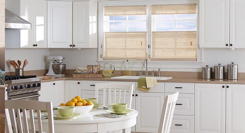 Tan window shades above a kitchen sink in a brightly lit kitchen