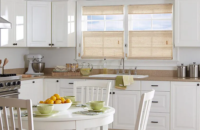 Tan window shades above a kitchen sink in a brightly lit kitchen