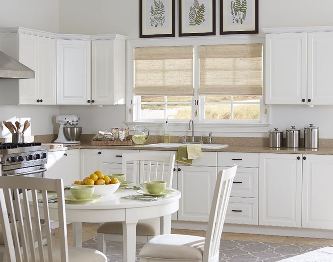 beige bamboo shades in a bright white kitchen
