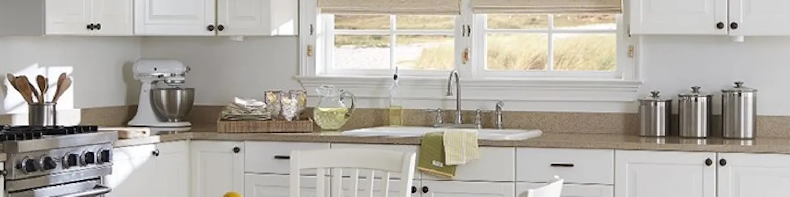 beige bamboo shades in a bright white kitchen