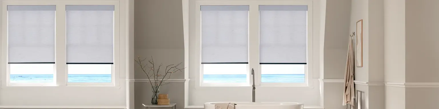 white roller shades in a brightly lit living room facing the ocean