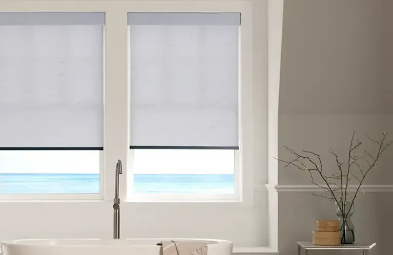 white roller shades in a brightly lit living room facing the ocean
