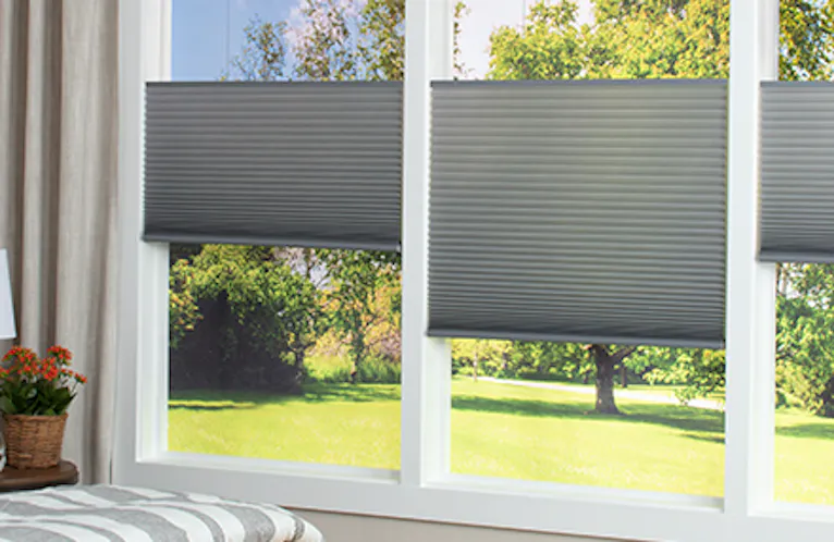 vignette close up of a gray hue cellular shades showing top down bottom up light control feature in a bedroom space.