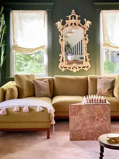white roman shades in dark living room gold mirror and couch