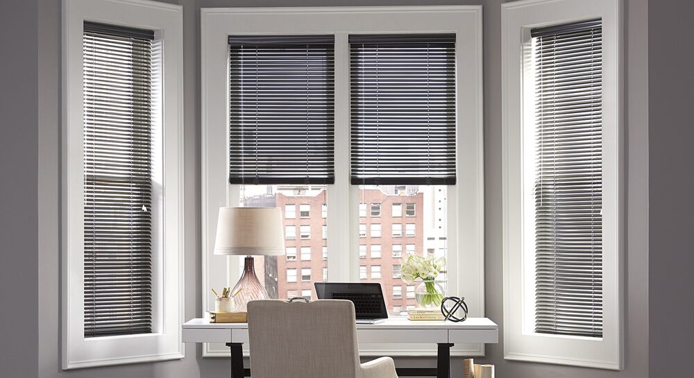 Metal mini blinds in the bay window of an office nook