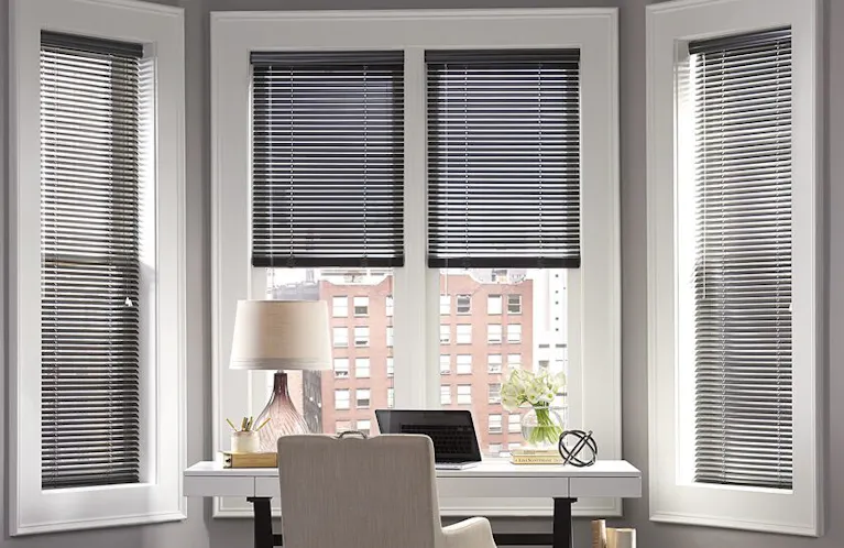 Metal mini blinds in the bay window of an office nook