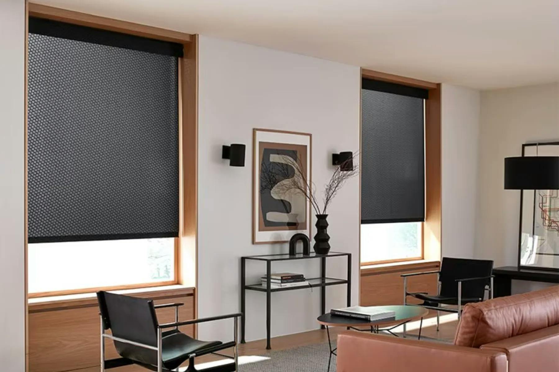 Room with mid century modern furniture, large windows and a leather couch. The windows are covered with black, light-filtering roller shades.