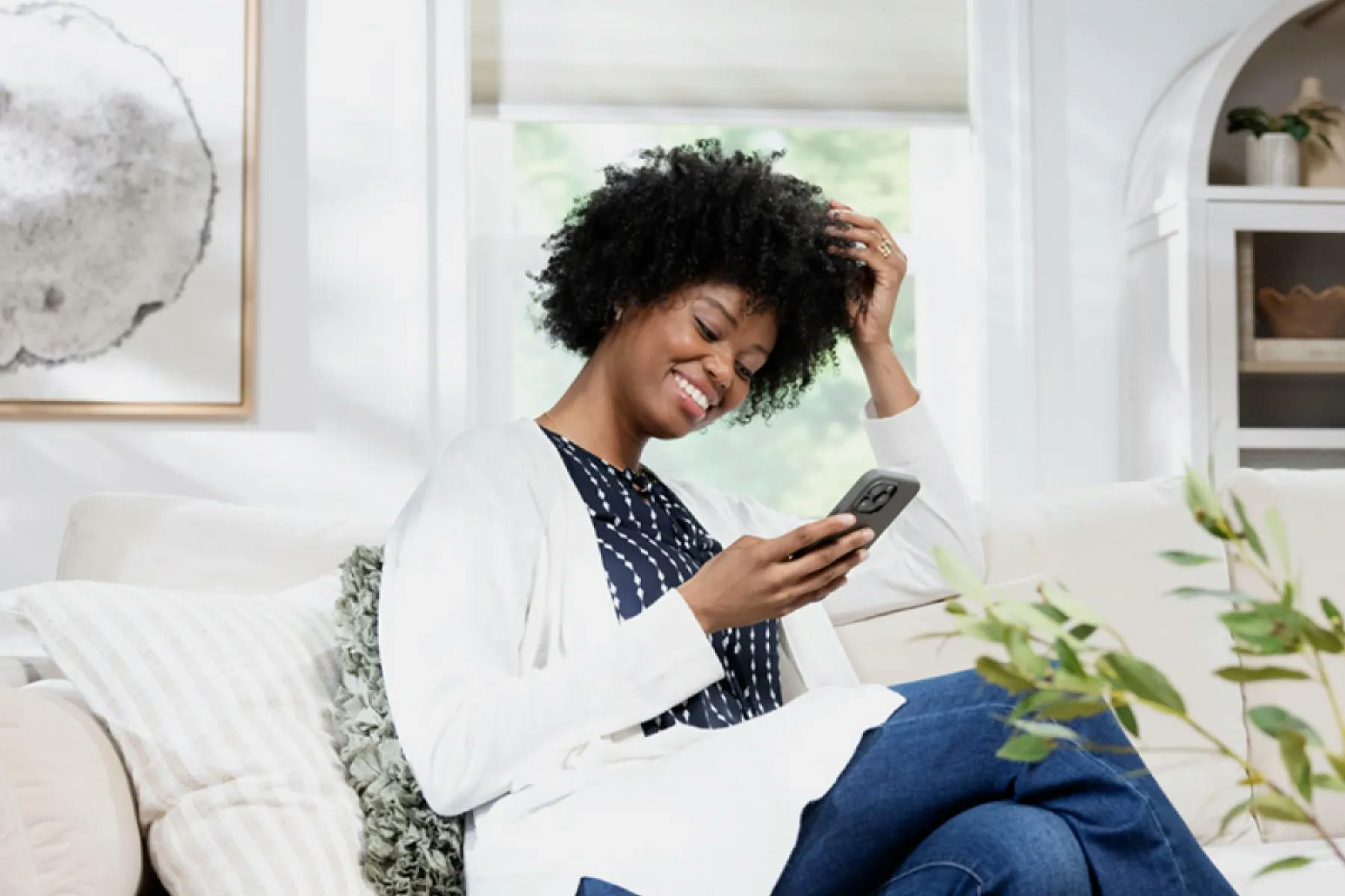 Woman sitting on her couch, using her phone.
