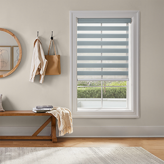 Window with soft blue zebra shades in a bright entryway, showing alternating sheer and solid bands for adjustable light control.
