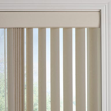 Neutral living space with beige vertical blinds on a tall window, styled with a wooden side table, green pillow, and potted plant