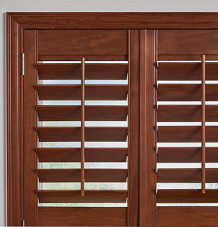 Living room featuring rich wooden plantation shutters framed by white molding, paired with a modern cream chair and gold accent table.