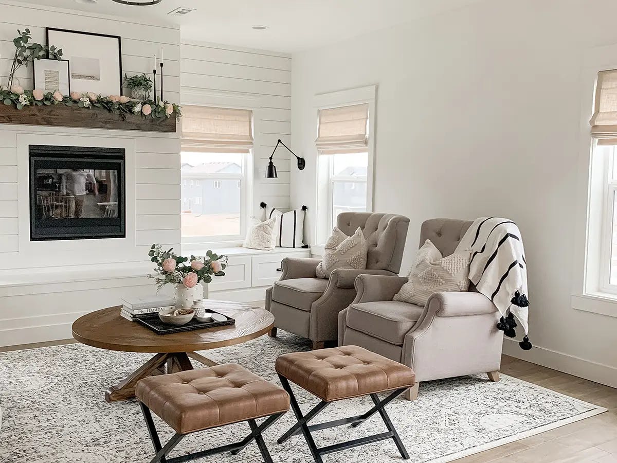 Bright living room with neutral decor, armchairs and a roman window shades.