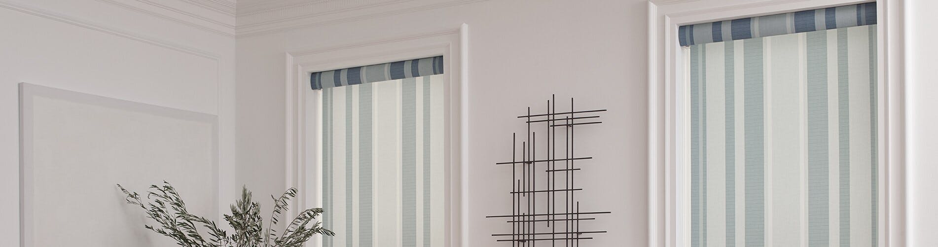 Striped roller shades with blue tones against an off-white wall