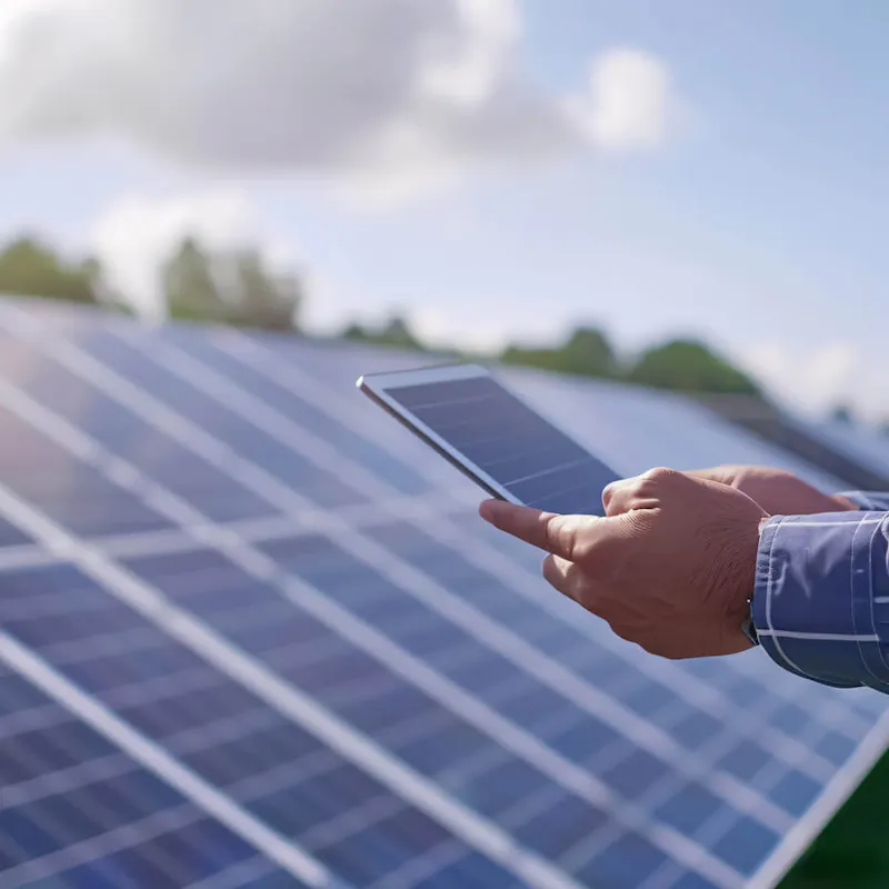 Techniker prüft den Wirkungsgrad einer Photovoltaikanlage mit einem Tablet vor Solarmodulen | Gelb Solar