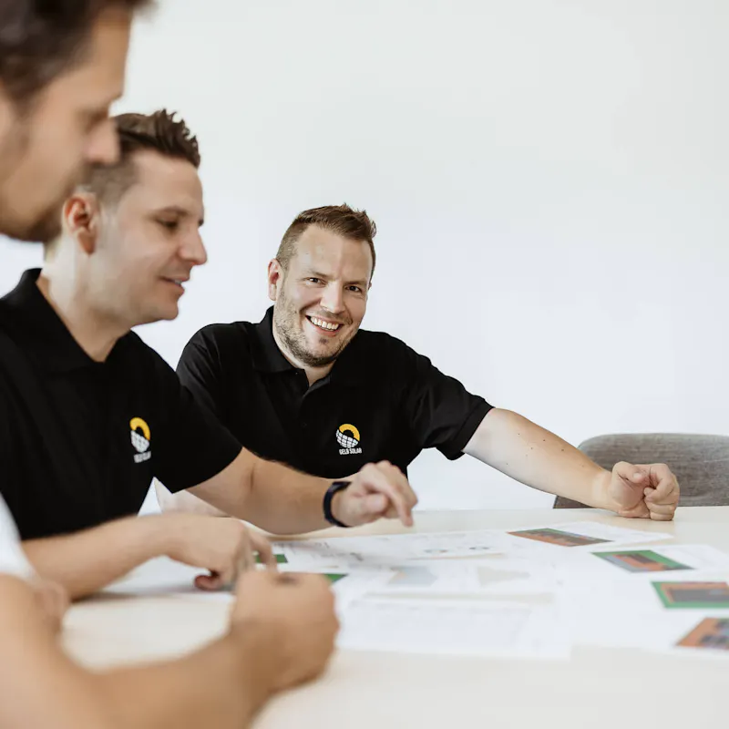 Gelb Solar Team sitzt mit einem Kunden zusammen und erklärt die Funktionsweise eines Stromspeichers Gelb Solar Team sitzt mit einem Kunden zusammen und erklärt die Funktionsweise eines Stromspeichers