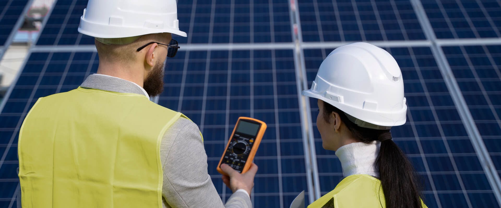 Zwei Monteure stehen vor Solaranlagen und planen den Einbau eines Optimierers