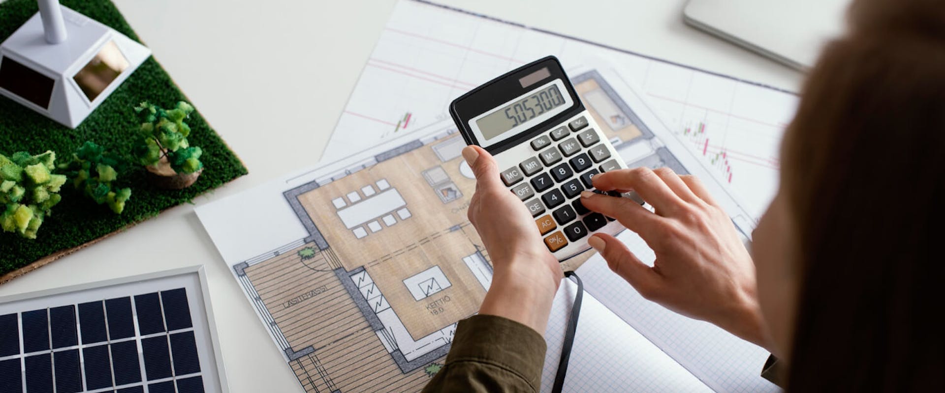 Frau berechnet die optimale kWp-Leistung einer Solaranlage auf Basis eines Hausplans – Planung der Anlagengröße im Kontext von Photovoltaik