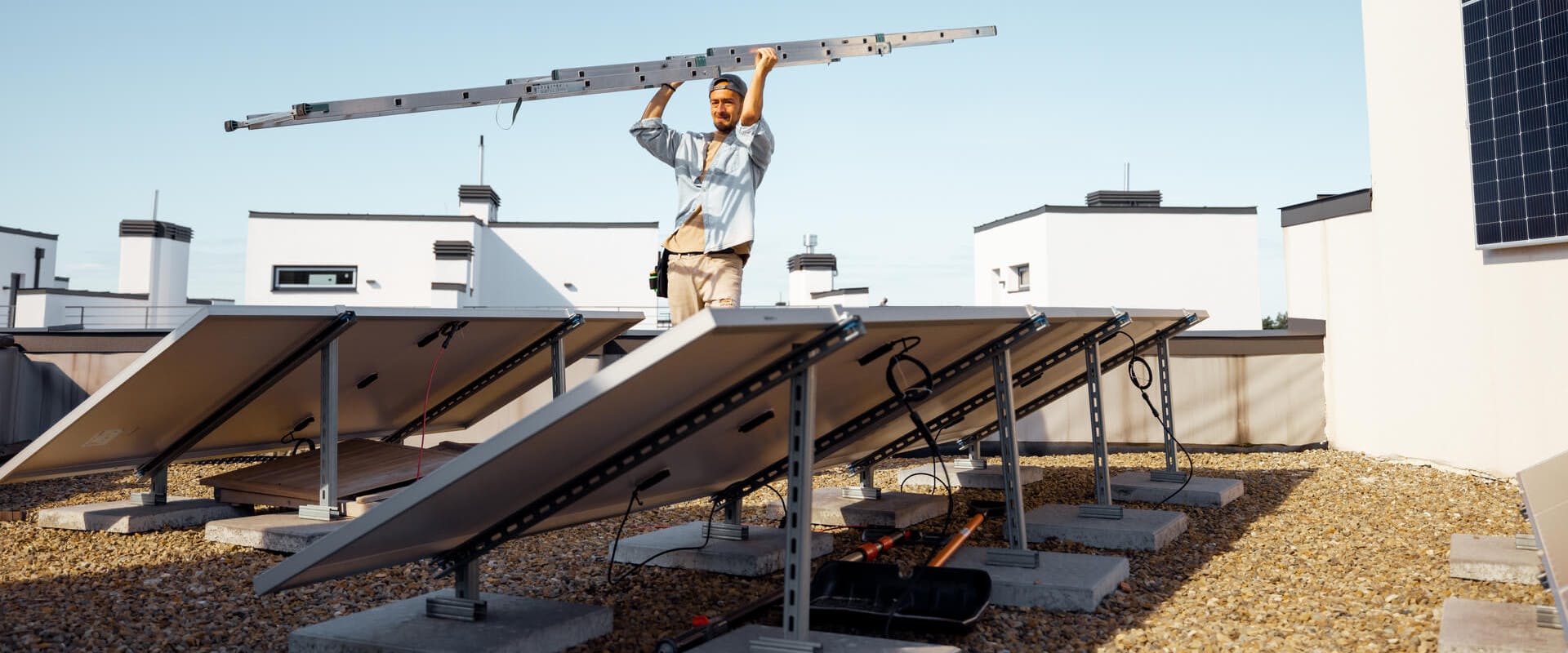 Monteur, der eine Solaranlage auf einem Flachdach installiert Monteur, der eine Solaranlage auf einem Flachdach installiert