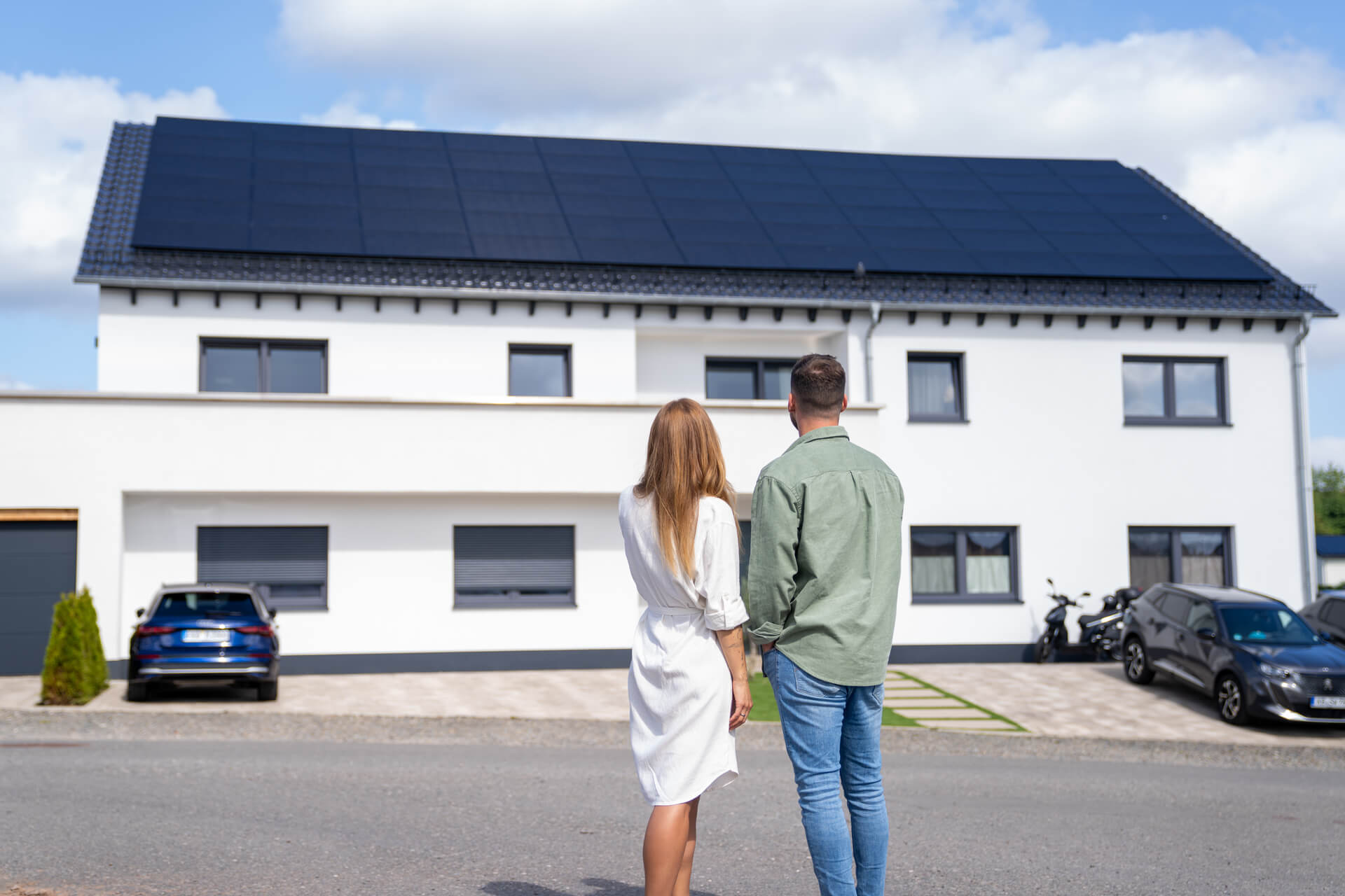 Paar schaut auf ein Mehrfamilienhaus mit Solaranlage auf dem Dach