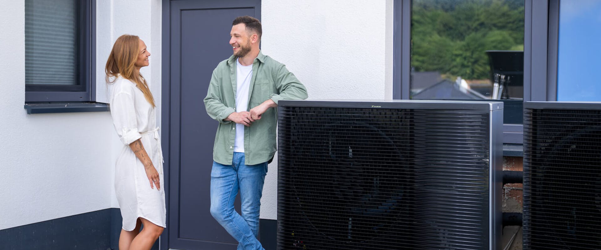 Junges Paar steht neben einer Wärmepumpe Junges Paar steht neben einer Wärmepumpe