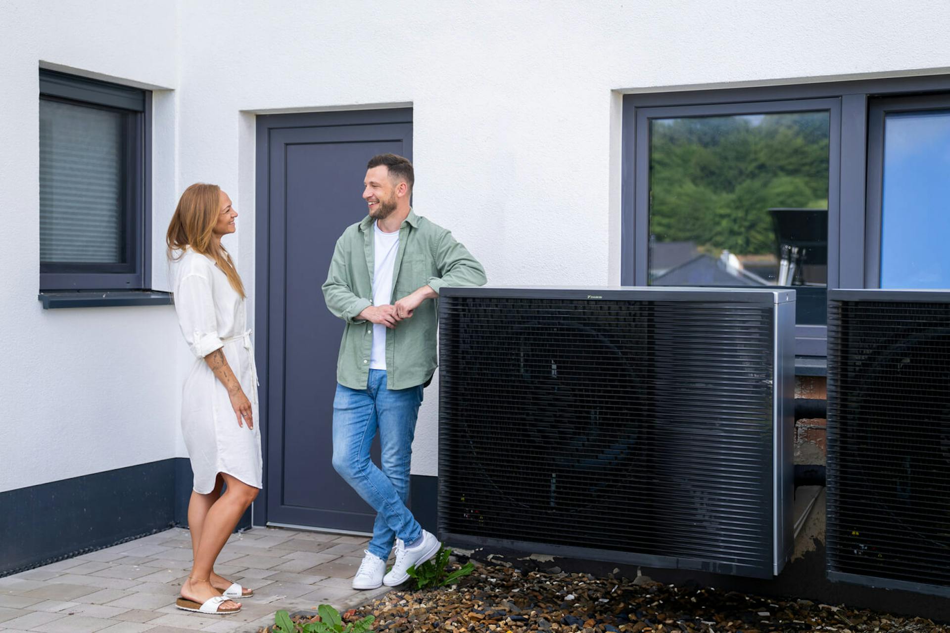 Paar, welches sich vor ihrer Wärmepumpe über Photovoltaik unterhält