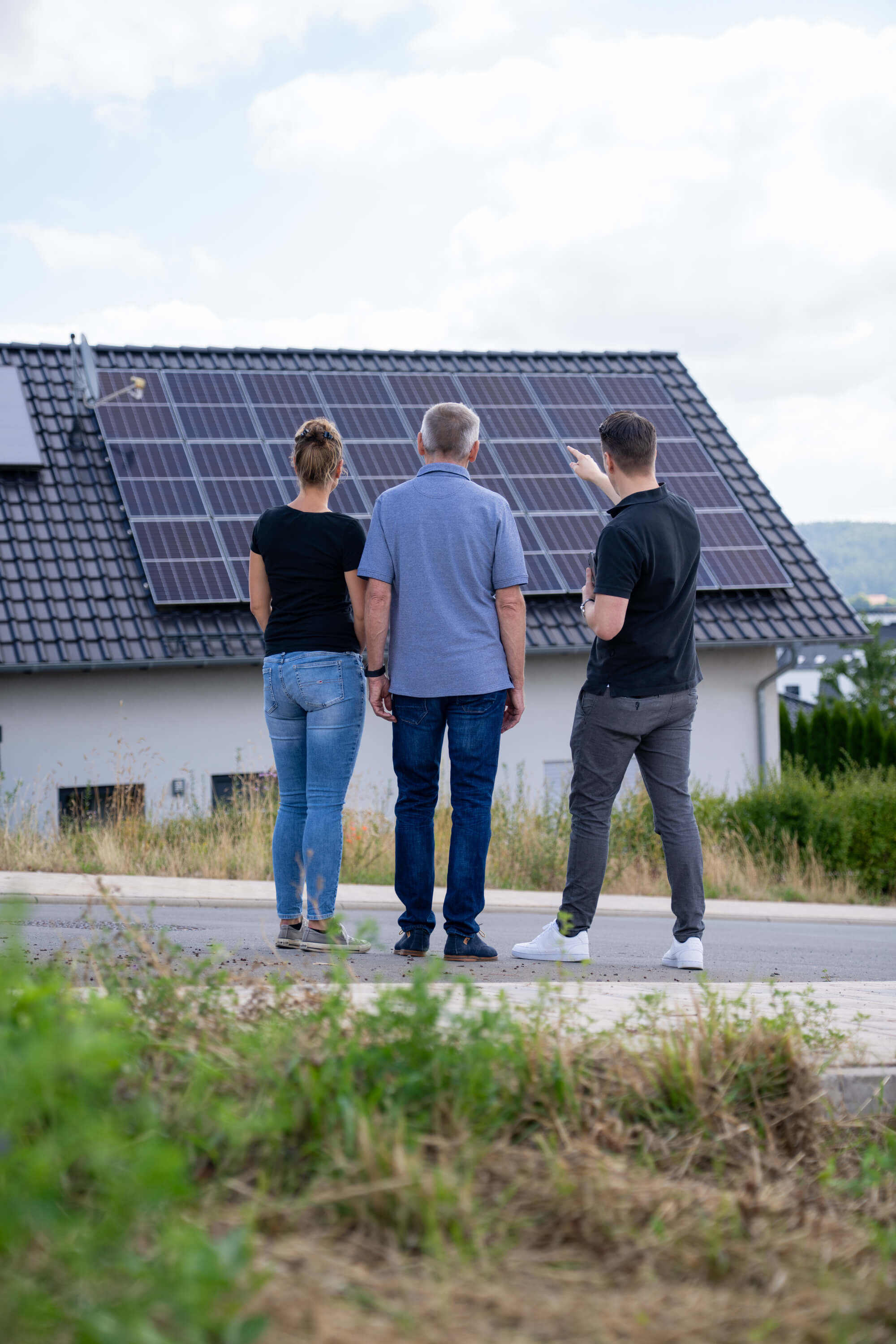 Älteres Paar, was vor einer Solaranlage auf dem Dach, beraten wird
