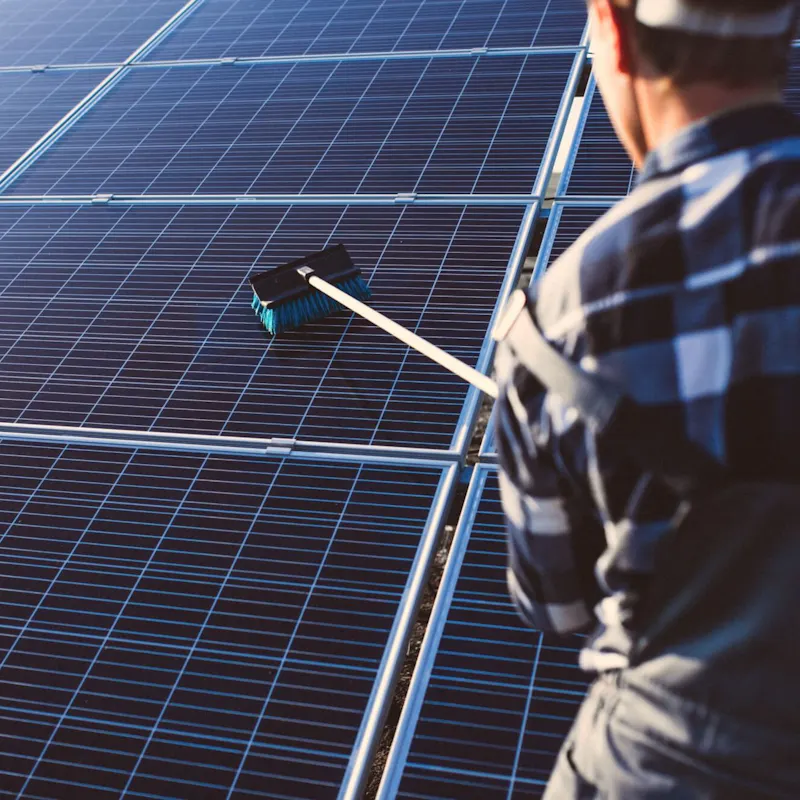 Mann reinigt eine Solaranlage Mann reinigt eine Solaranlage