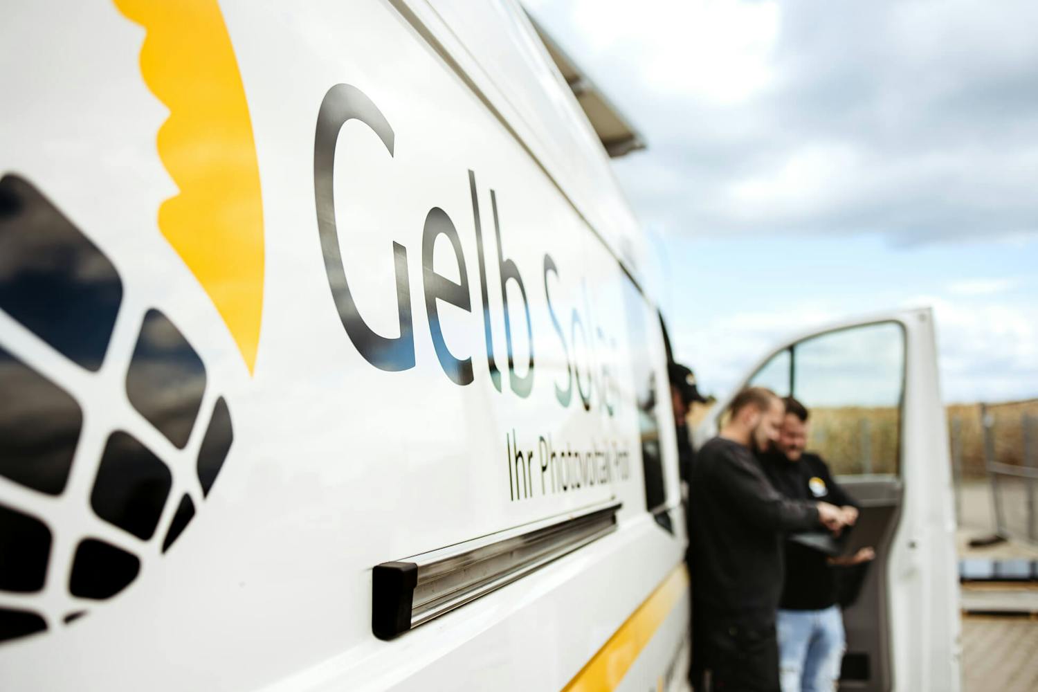 Nahaufnahme von dem Gelb Solar Fahrzeug-Logo, während im Hintergrund an einem Konzept gearbeitet wird