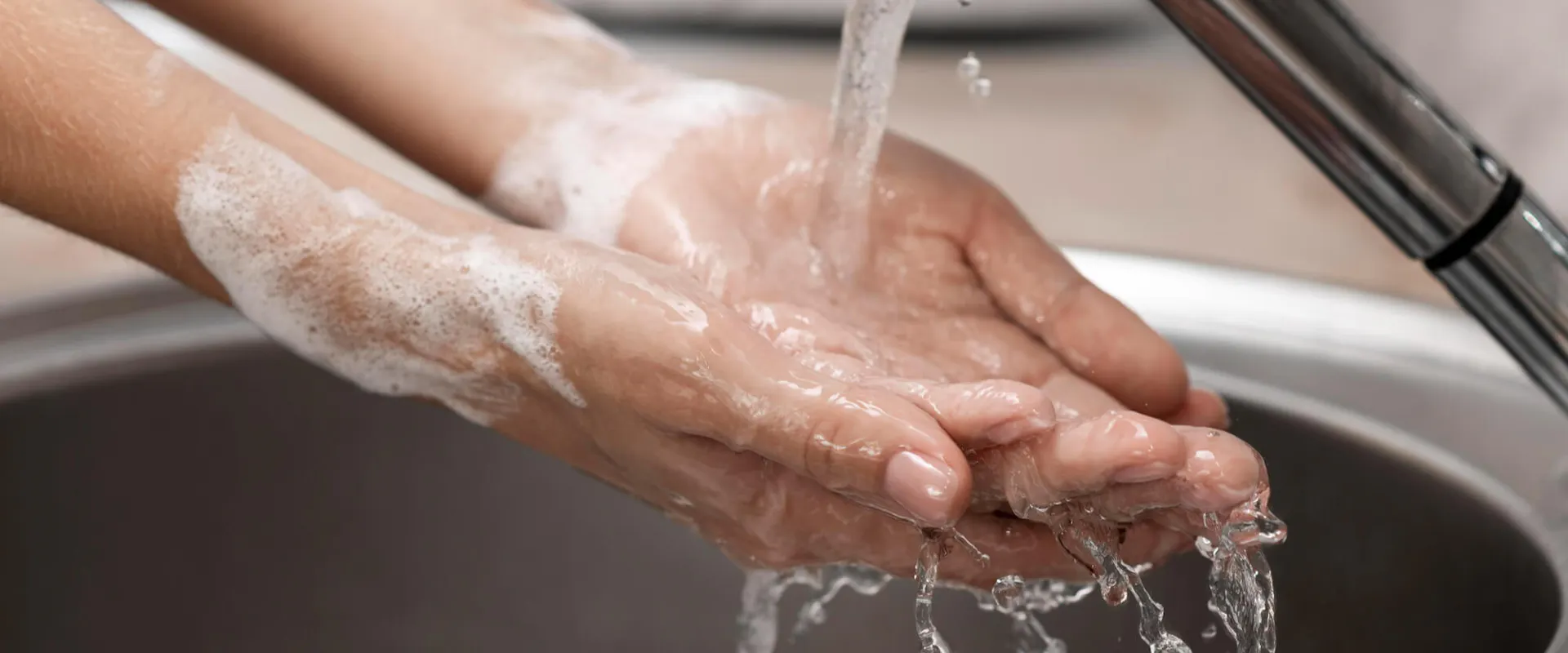 Person wäscht sich die Hände an einem Waschbecken Person wäscht sich die Hände an einem Waschbecken