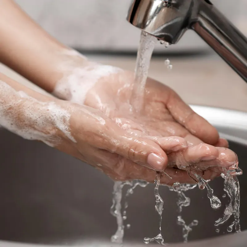 Person wäscht sich die Hände an einem Waschbecken Person wäscht sich die Hände an einem Waschbecken