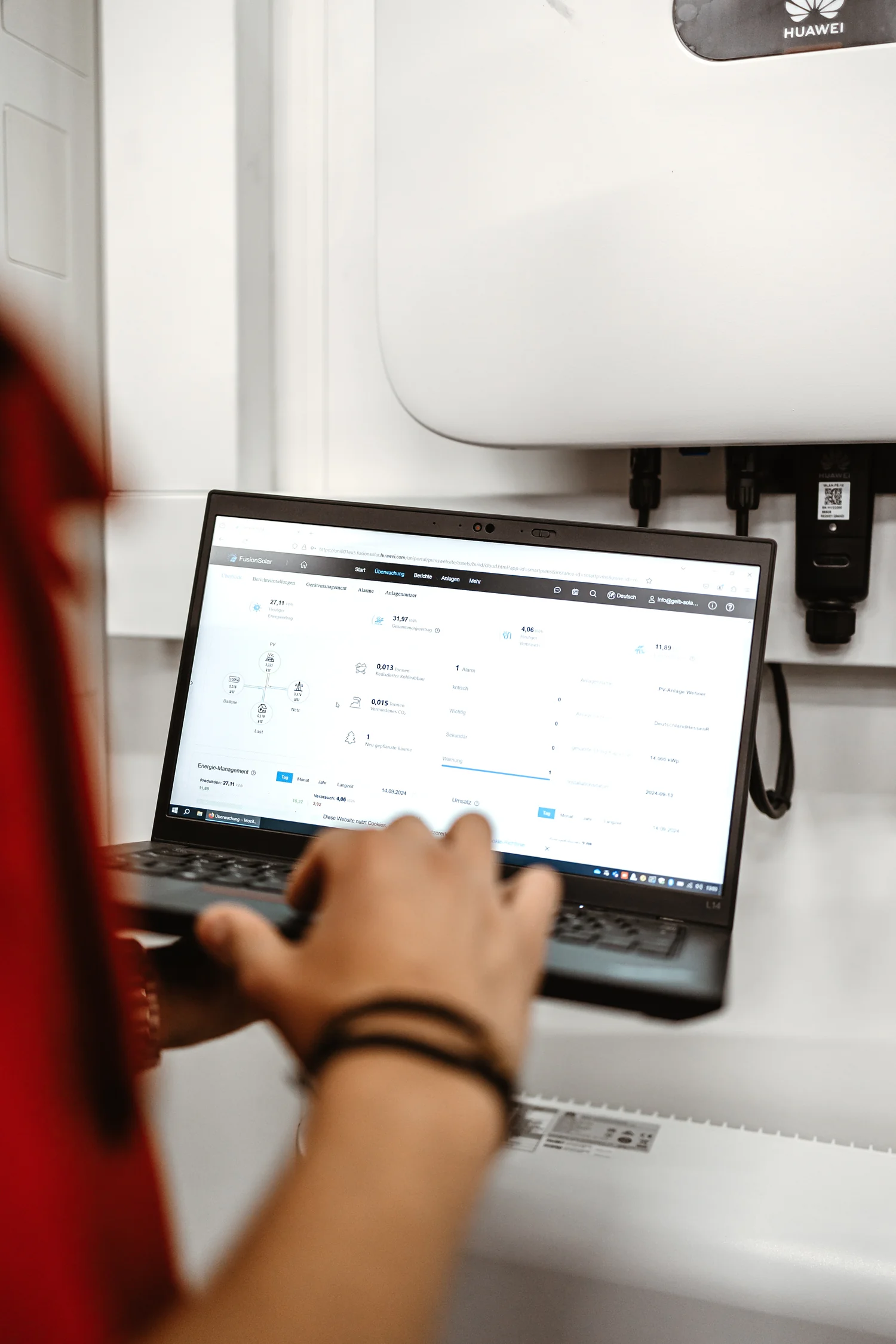 Techniker ruft FusionSolar-Monitoring auf dem Laptop auf – Huawei Wechselrichter im Hintergrund | Gelb Solar