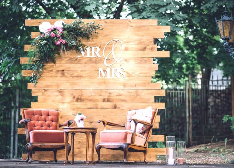 Etrafta ağaçların bulunduğu bir alan önünde; iki adet eski moda tekli koltuk ve koltukların arasında bir sehpa bulunuyor. Koltukların arkasında tahtalardan yapılmış ve üzeri çiçek ile süslenmiş bir dekor duruyor. Dekorun üzerinde İngilizce olarak "Mr & Mrs" yani "Bay ve Bayan" yazıyor.