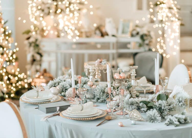 Kış teması ile süslenmiş olan düğün salonunda daire şeklinde bir yemek masası bulunuyor. Masanın üzerinde mumlar, tabaklar, kaşıklar ve kış ruhunu yansıtan çam ağacı dalları duruyor. Arka planda ağaçlar ve dekor üzerine eklenmiş ışıklandırmalar görünüyor.