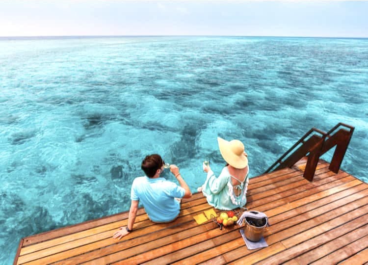 Balayında olan genç çift, iskelede yemek yerken ve içeceklerini içerken, bir yandan da okyanusu seyrediyor. 