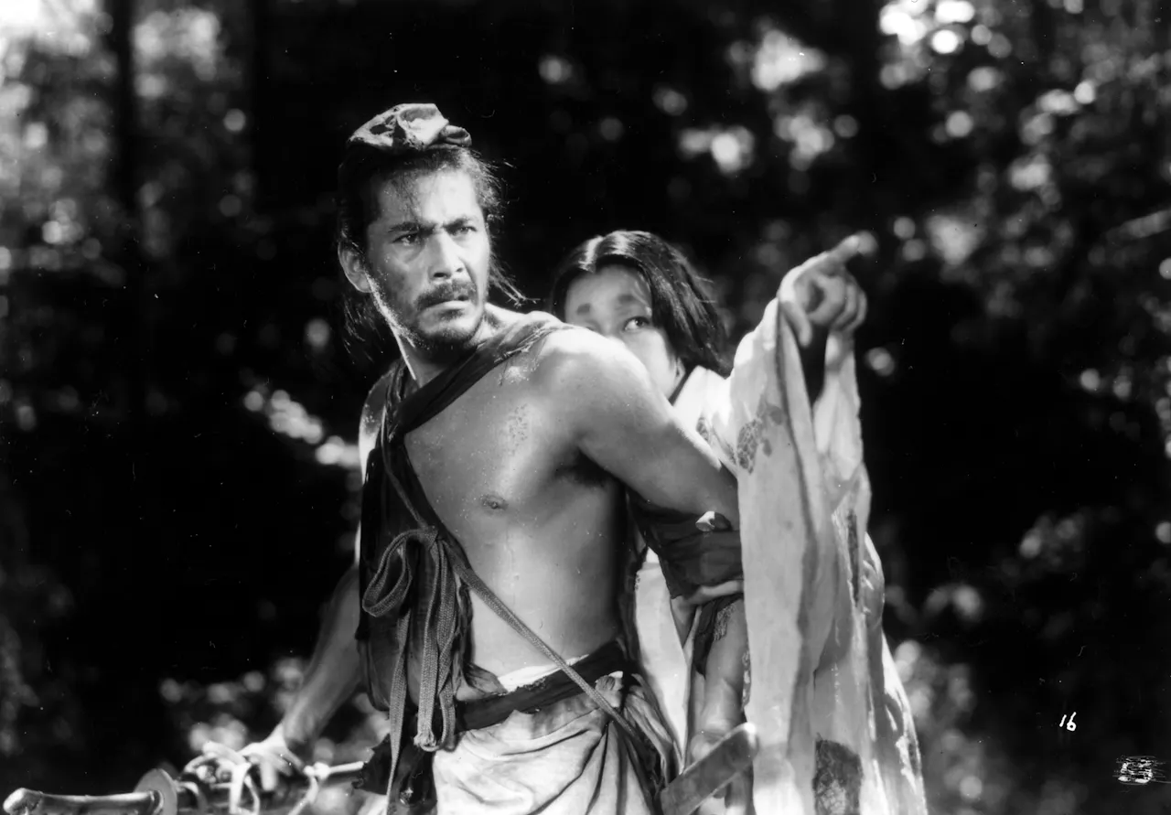 Toshiro Mifune and Machiko Kyō in Rashomon (1950). Daiei press photo, public domain, via Wikimedia Commons.