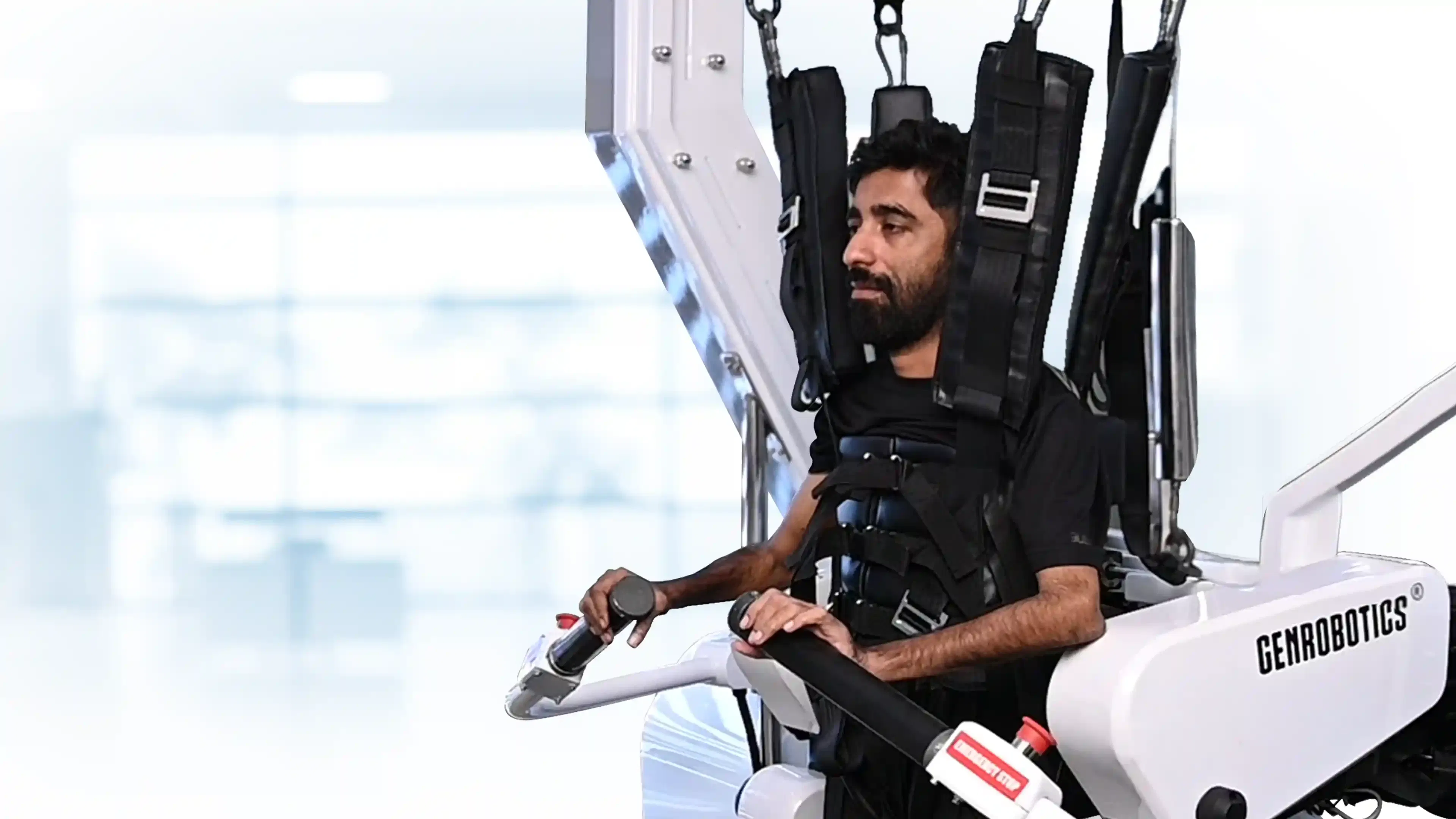 A man supported in a robotic gait training system, holding the device handles while undergoing a structured rehabilitation session.
