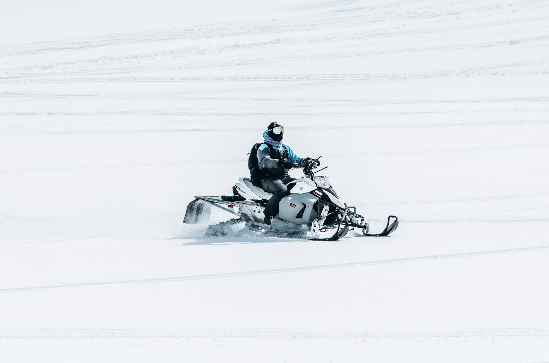 A man riding a snowmobile in a large snowy field