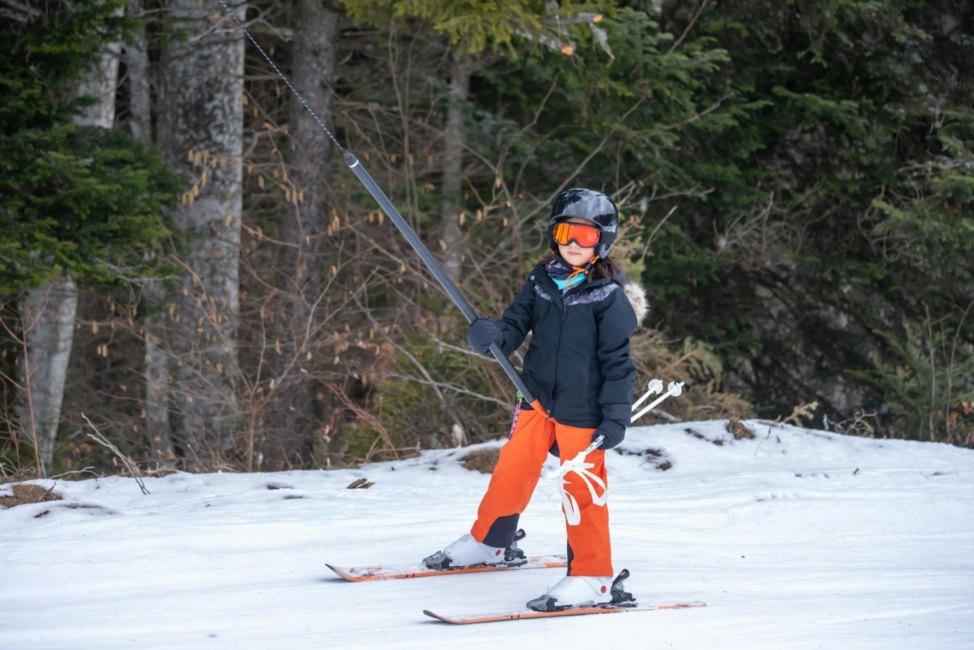 Portrait of smiling girl holding ski while standing in snow