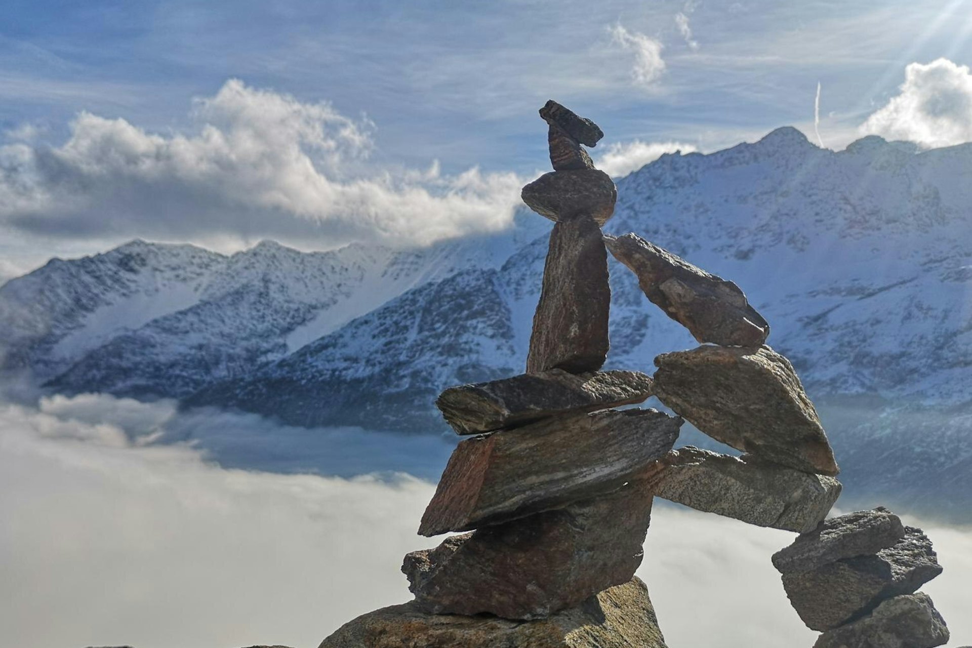 Stack of rock on snowcapped mountain against sky