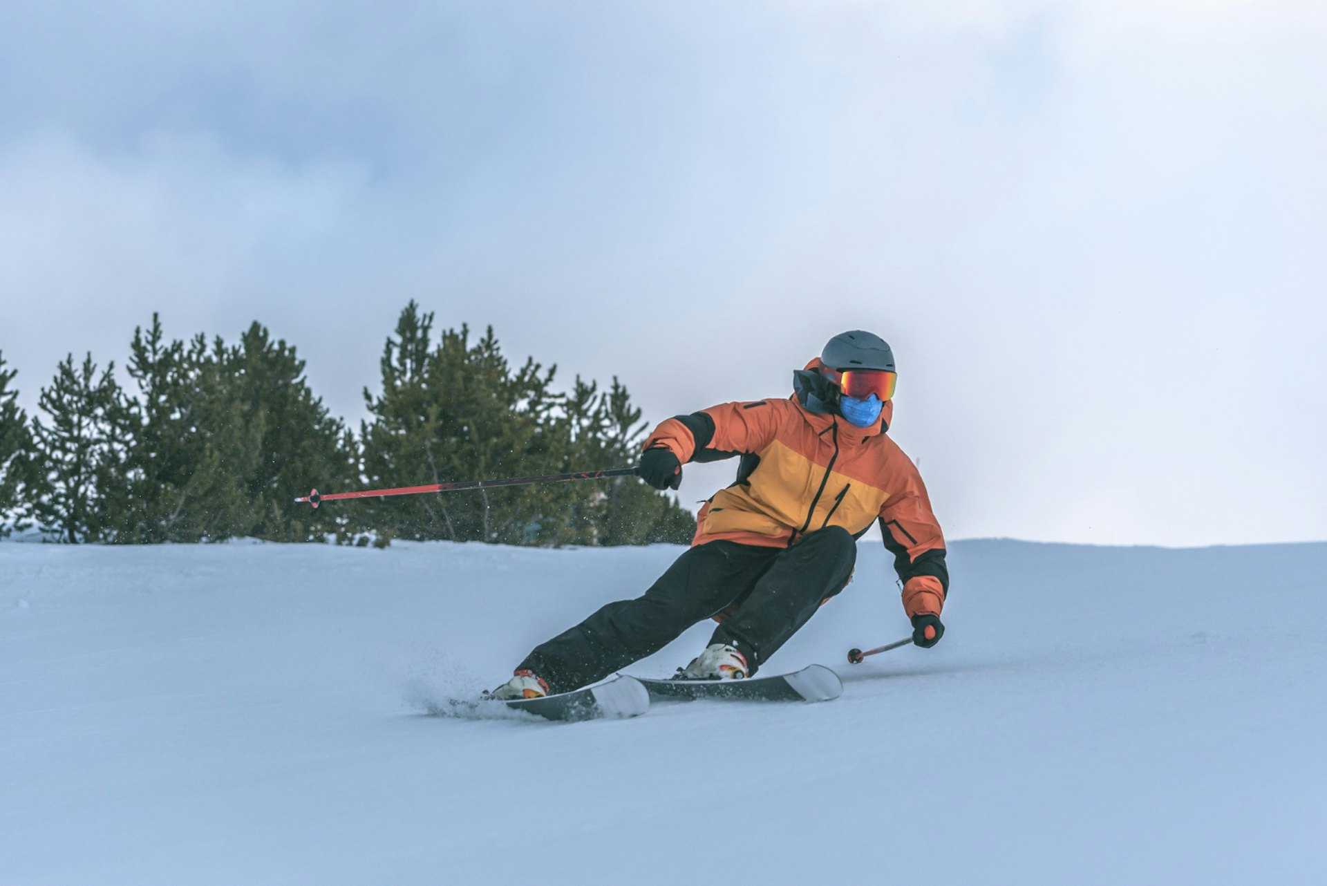 Skier of undiscernible gender in orange ski jacket hitting the slopes at Whistler Blackcomb in British Columbia, Canada.