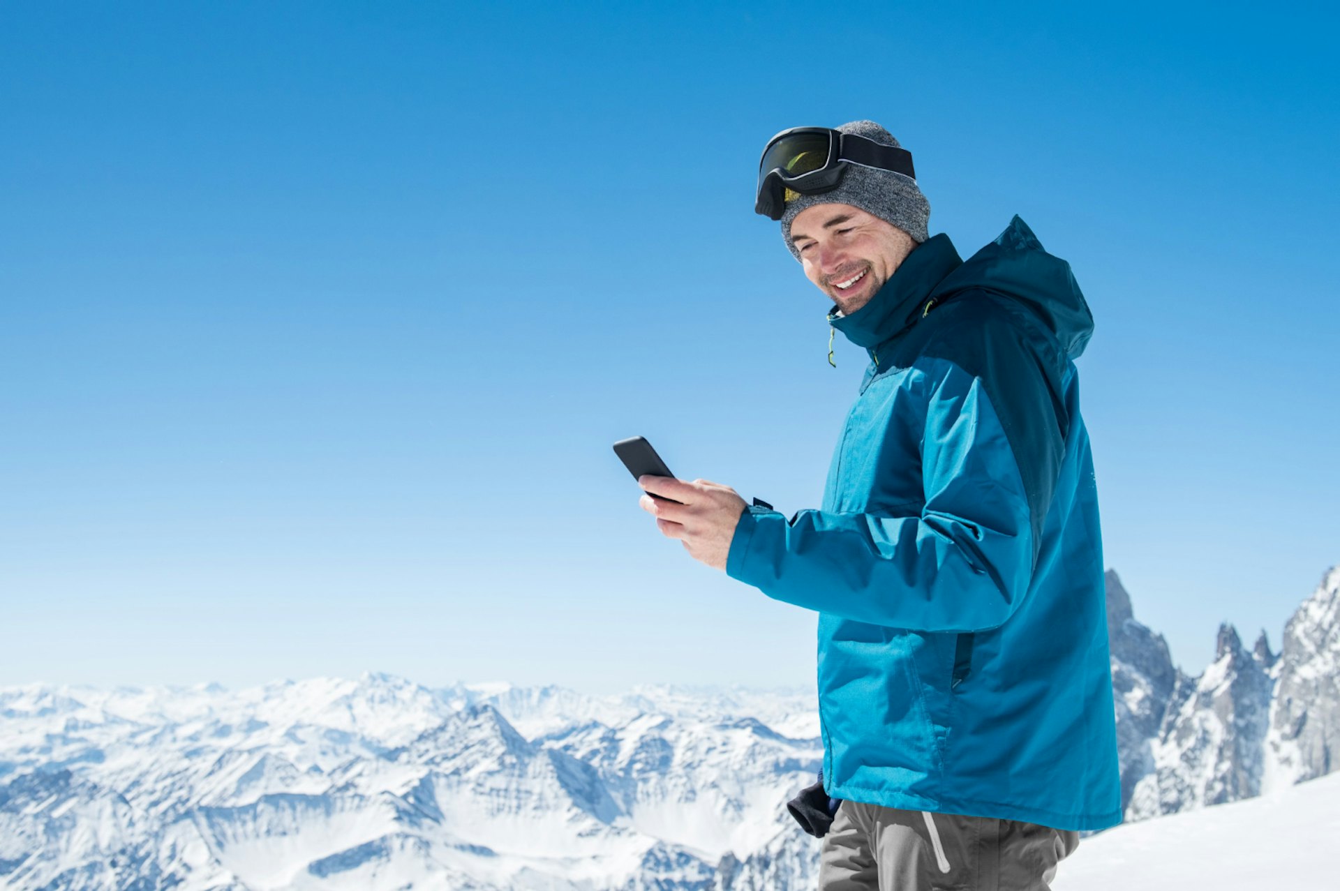 A man holding a phone on a snowy mountain