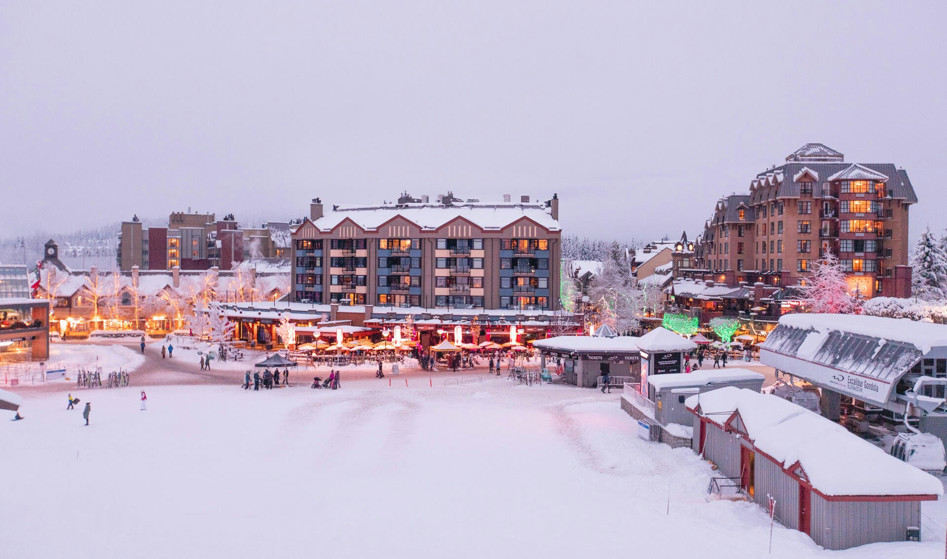 A snowy town scene featuring illuminated buildings and twinkling lights against a winter backdrop.