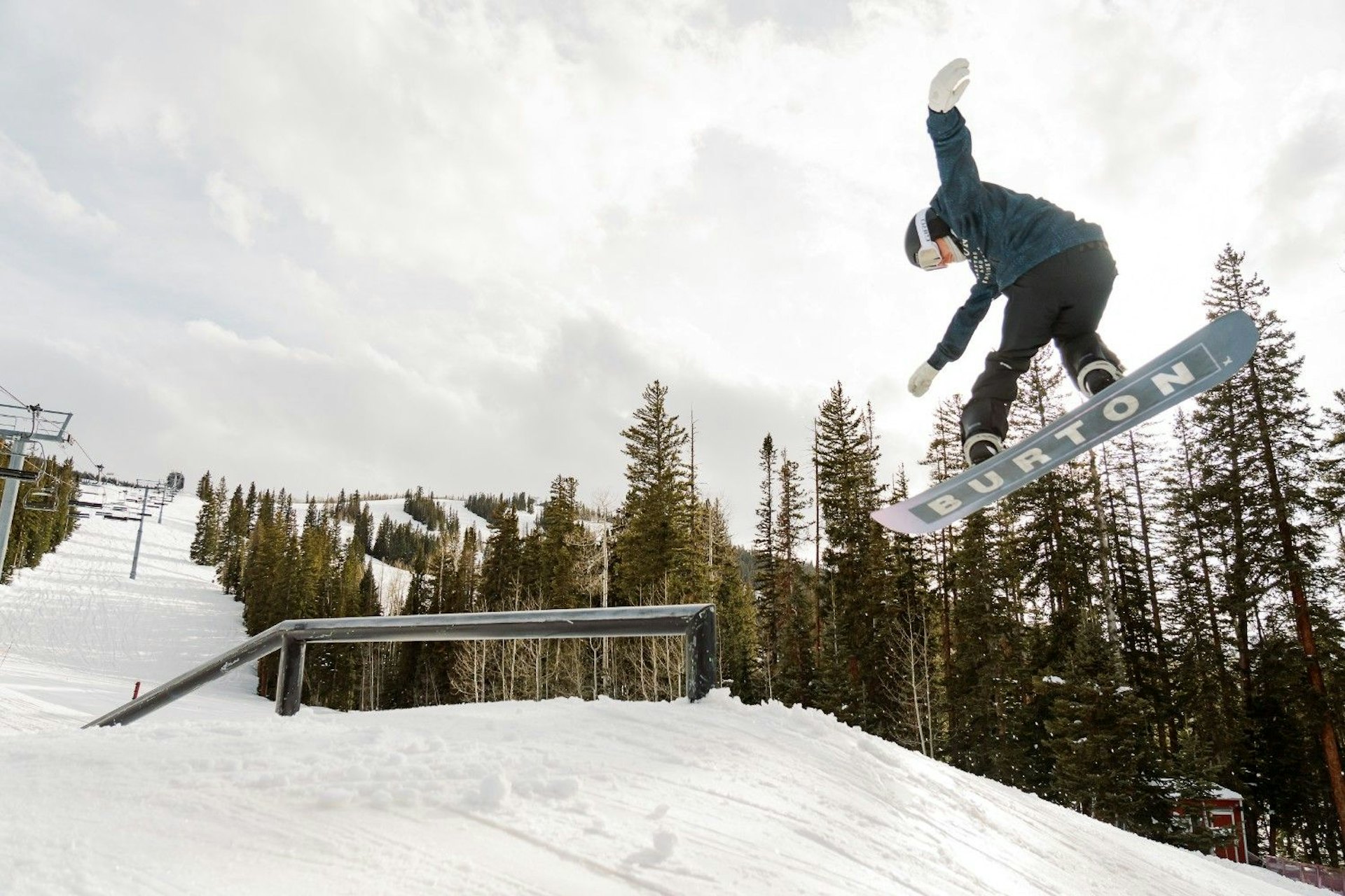 Male snowboarder in dark coloured hitting the terrain park at Snowmass in Colorado, USA.