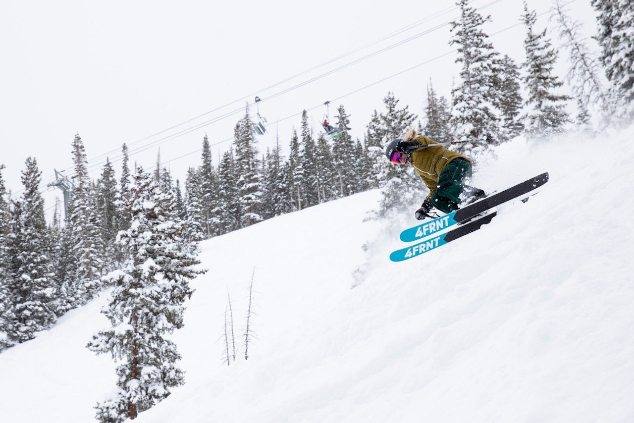 Female skier in olive green ski jacket hitting the slopes at Snowmass in Colorado, USA.