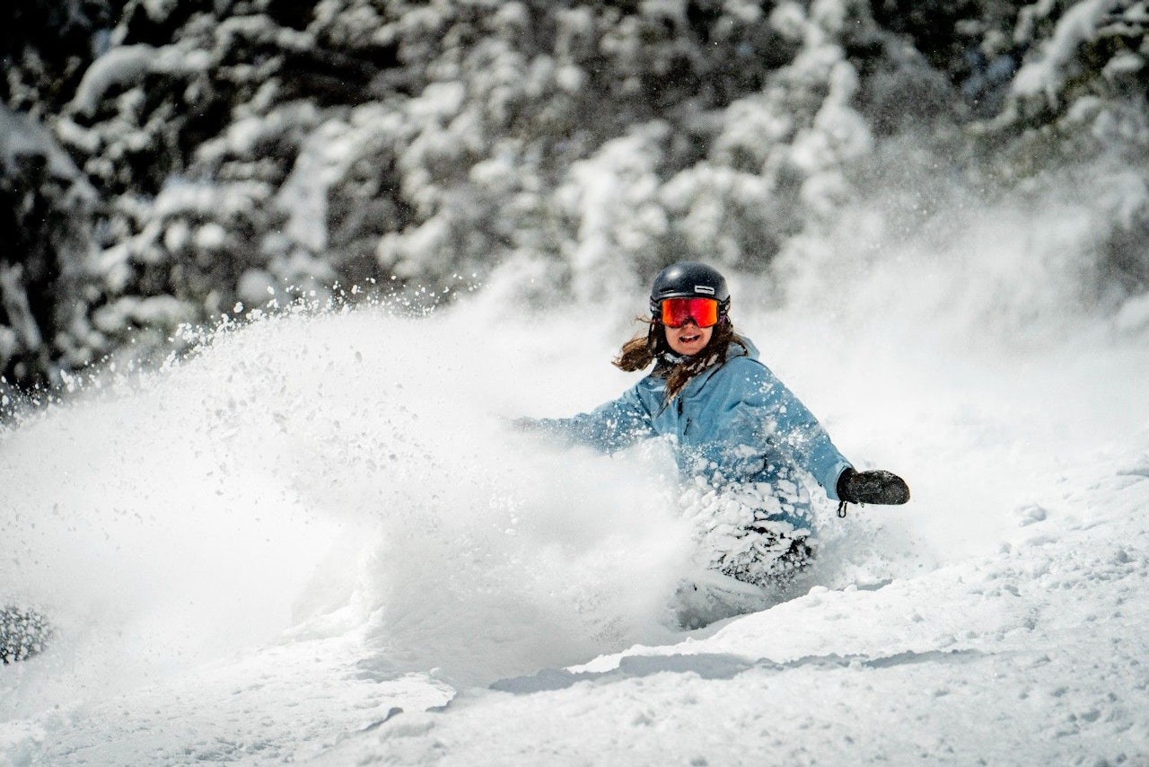 Female snowboarder in light blue snowboarding attire hitting the slopes at at Snowmass in Colorado, USA.